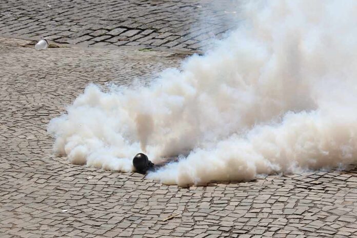 Smoke grenade releasing a thick cloud on a cobblestone street